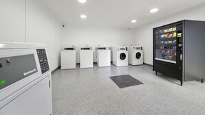 A laundry facility with multiple washing machines and a vending machine.
