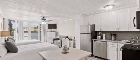 A modern kitchen with white cabinetry, a refrigerator, and a dining area with a table and chairs.