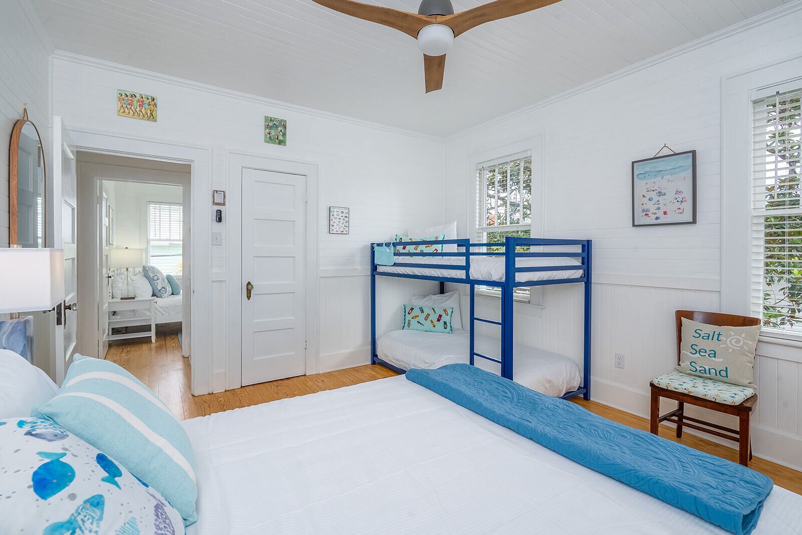 A bedroom with a bunk bed, a desk, a chair, and a window with blinds.