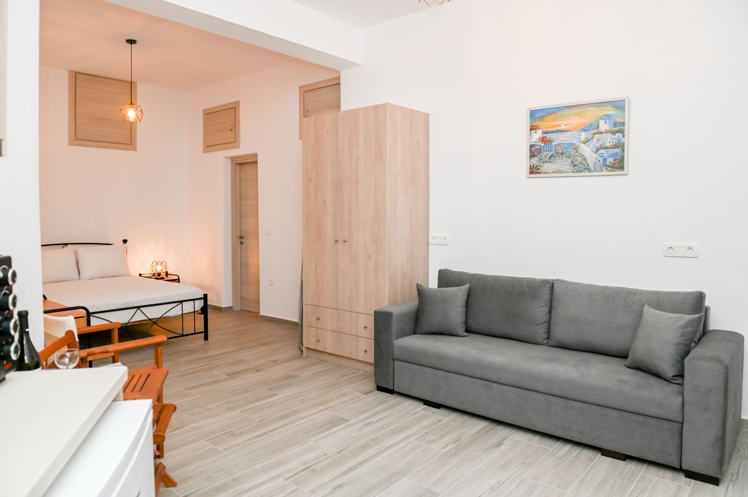 Un salon moderne avec un canapé gris, une armoire en bois et un tableau accroché au mur.