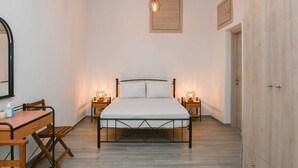A bedroom with a bed, bedside tables, a desk with a chair, a hanging light fixture, and a wardrobe. - Experience Dreamy Santorini Gorgeous Std (Santorini)