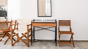 A compact room with a wooden desk, a chair, and a mirror on the wall. - Experience Dreamy Santorini Gorgeous Std (Santorini)