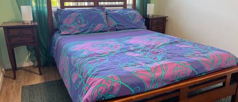 A bed with a floral-patterned bedspread, two bedside tables with lamps, and a window with curtains.