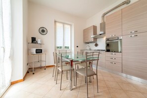 Une cuisine moderne avec une table à manger en verre, des chaises en métal et des meubles de rangement en bois.