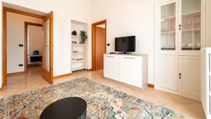 A modern living room with a flat-screen TV, a white cabinet, a patterned rug, and a door leading to another room. - Bright and Cozy in Menaggio by Wonderful Italy (Menaggio)