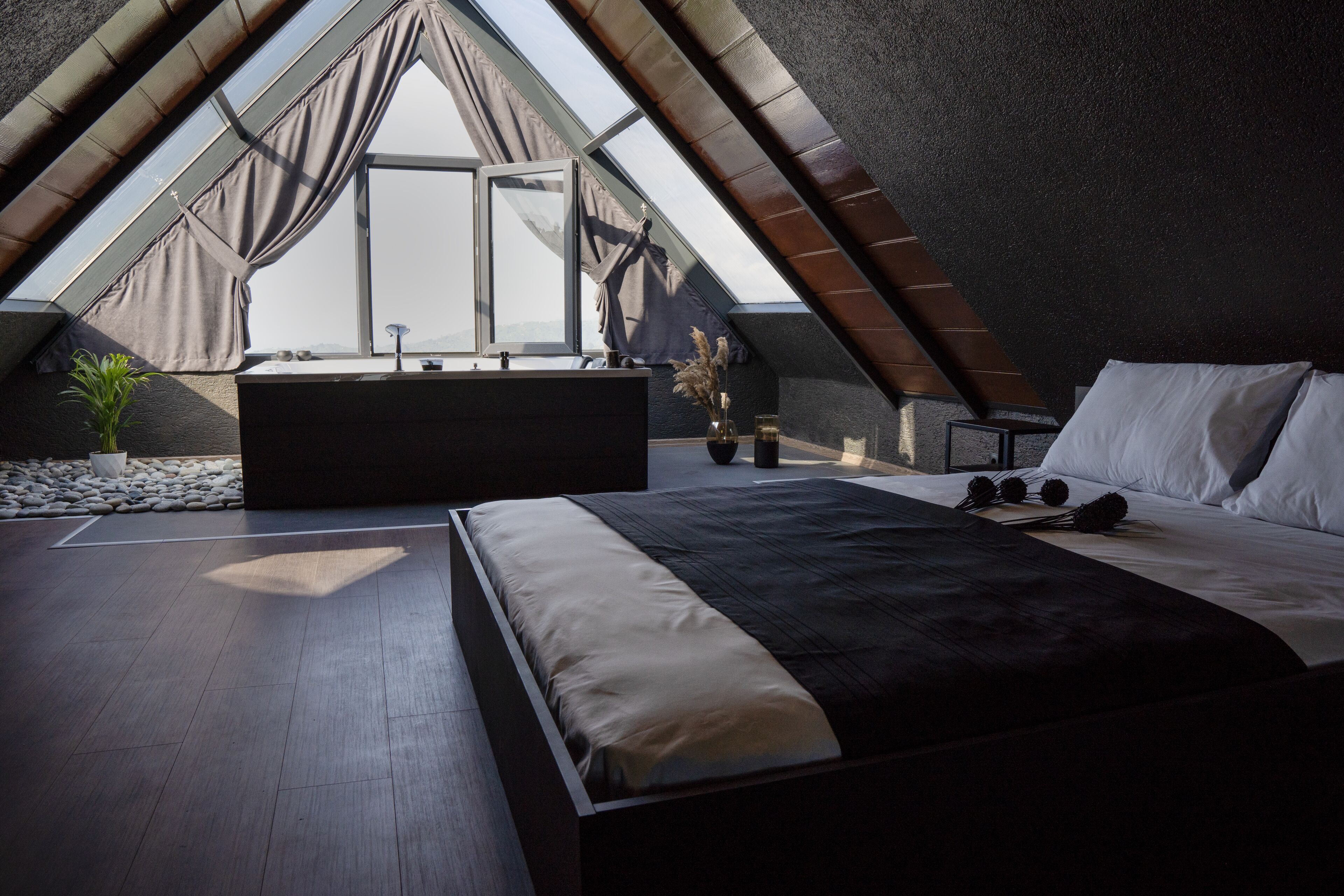 A bedroom with a large bed, a small table, and a window with curtains.