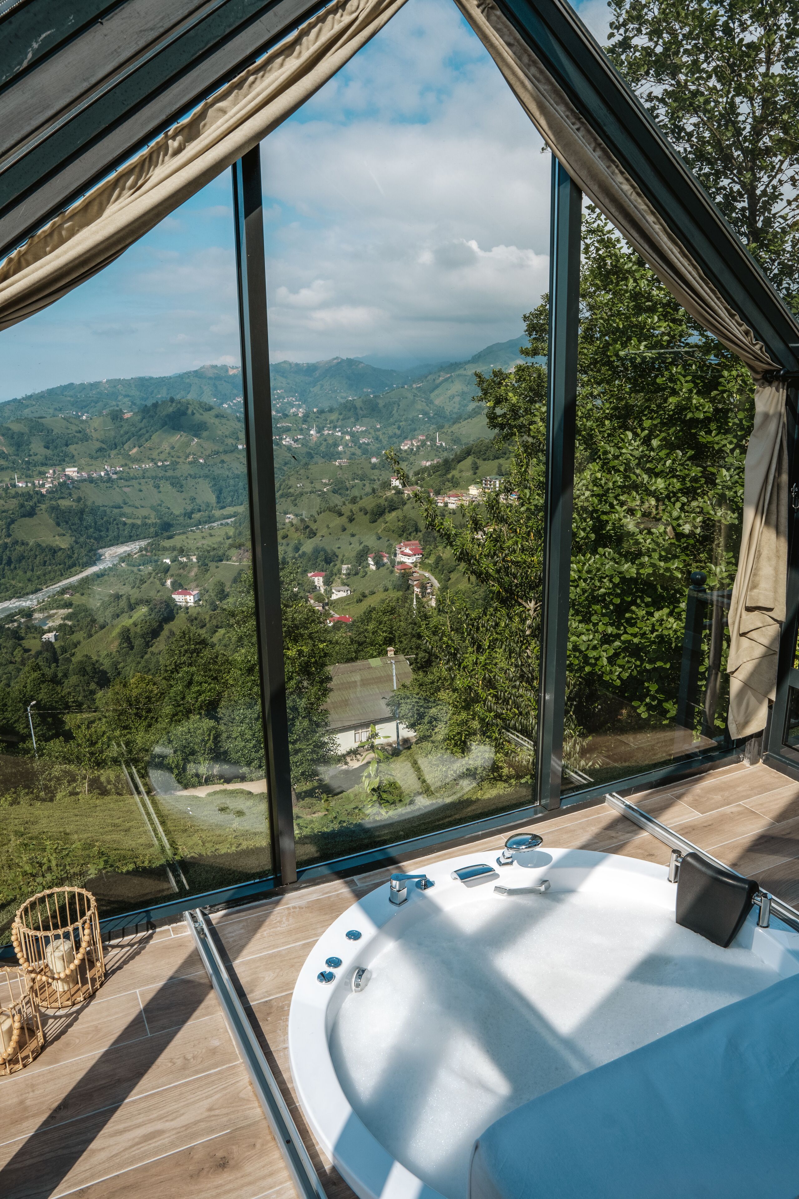 A modern bathroom with a large bathtub, a glass-enclosed shower area, and a view of a mountainous landscape.