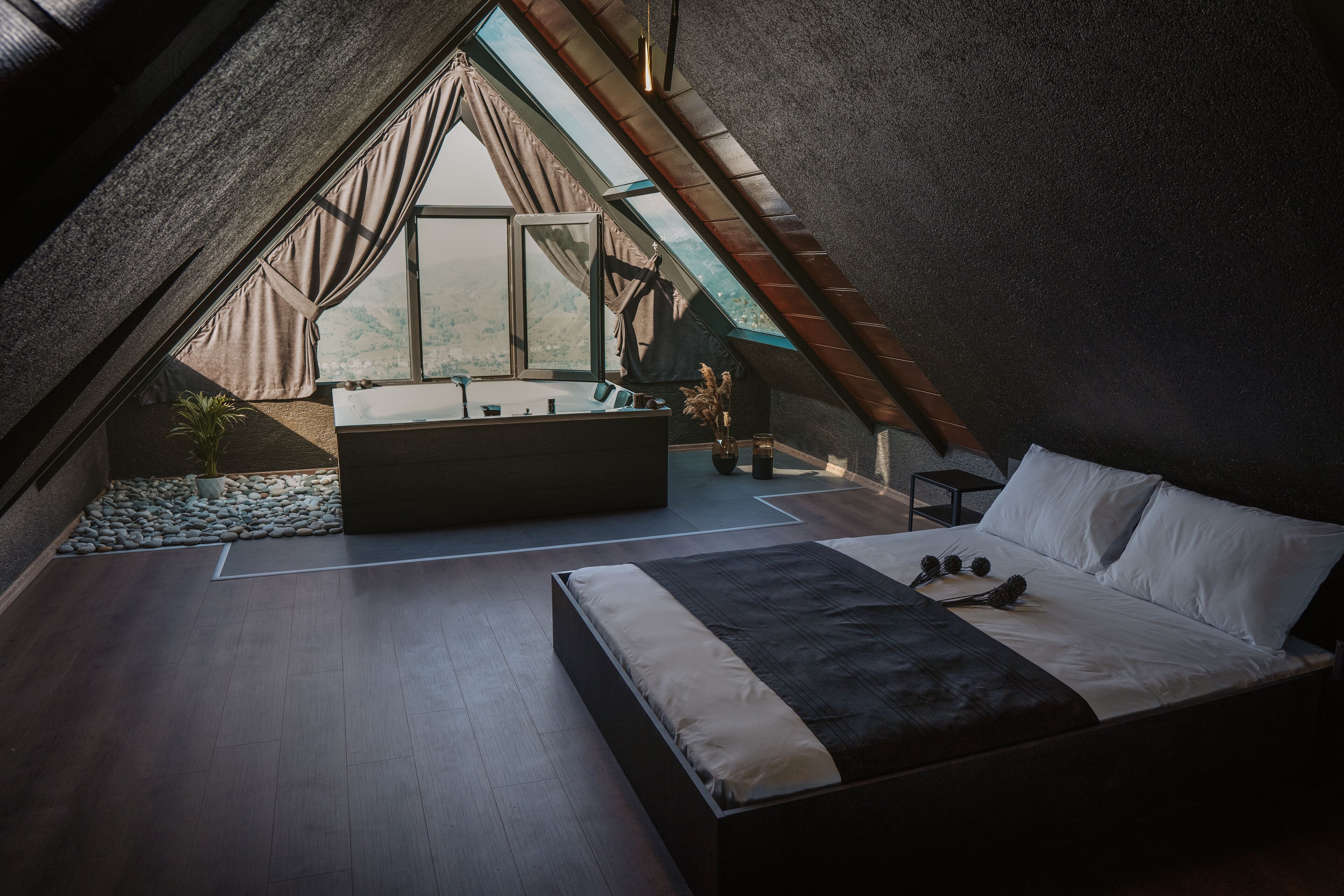 A modern bedroom with a large bed, a small seating area, and a view of the outdoors.