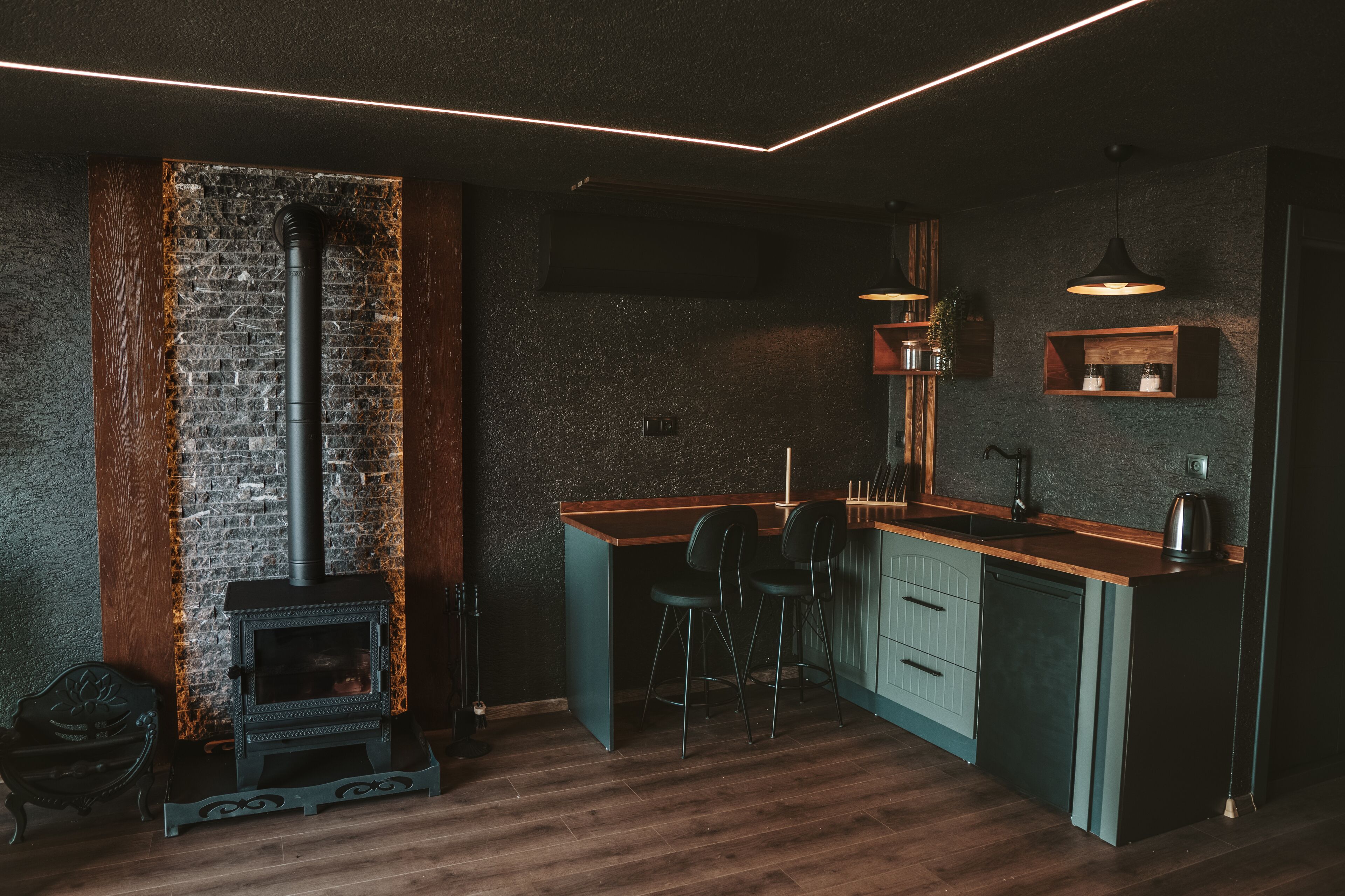 Una cocina compacta con estufa integrada, taburetes de bar y encimera de madera.