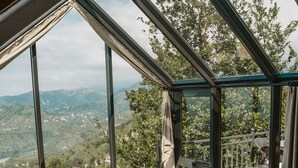 A bedroom with a large skylight, a wooden bed, and a view of a mountainous landscape.