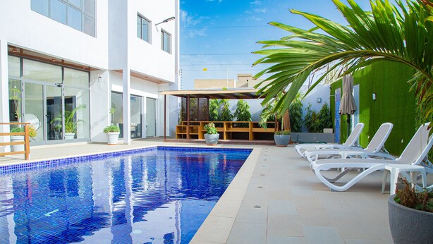 A swimming pool with lounge chairs and potted plants.