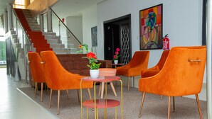 A modern interior with orange chairs, a small round table, and a potted plant.