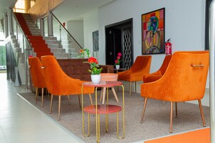 Ein modernes Interieur mit orangefarbenen Stühlen, einem kleinen runden Tisch und einer Topfpflanze.