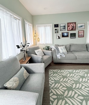 A living room with two grey sofas, a coffee table, and a patterned rug. - "Hina Hideaway", Views, A/C, Walkable to Beach (Punaluu)