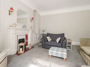 Ein Wohnzimmer mit Kamin, einer Couch, einem Hocker und einem kleinen Tisch.