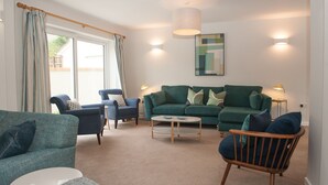 A living room with a sofa, chairs, a coffee table, and a lamp. - Brooklands (Lyme Regis)