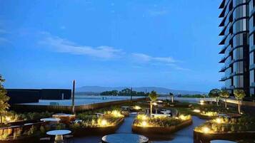An outdoor terrace with seating areas, a water feature, and a view of the water body.