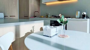 A modern kitchen with a white countertop, a vase with flowers, and a tissue box. - Skygarden Luxury 2-Bed, 2-Bath Apartment with Free Parking in Central Location (Glen Waverley)