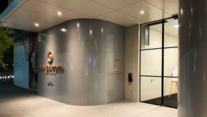 A modern building entrance with a curved facade, a digital display, and a sign indicating the address. - Skygarden Luxury 2-Bed, 2-Bath Apartment with Free Parking in Central Location (Glen Waverley)