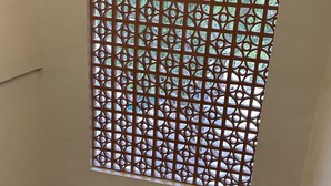 Un escalier avec une rampe en métal, une fenêtre décorée et un luminaire au plafond.