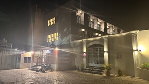 Un hôtel à la façade en briques, doté de nombreuses fenêtres et d’une entrée fermée par un portail.