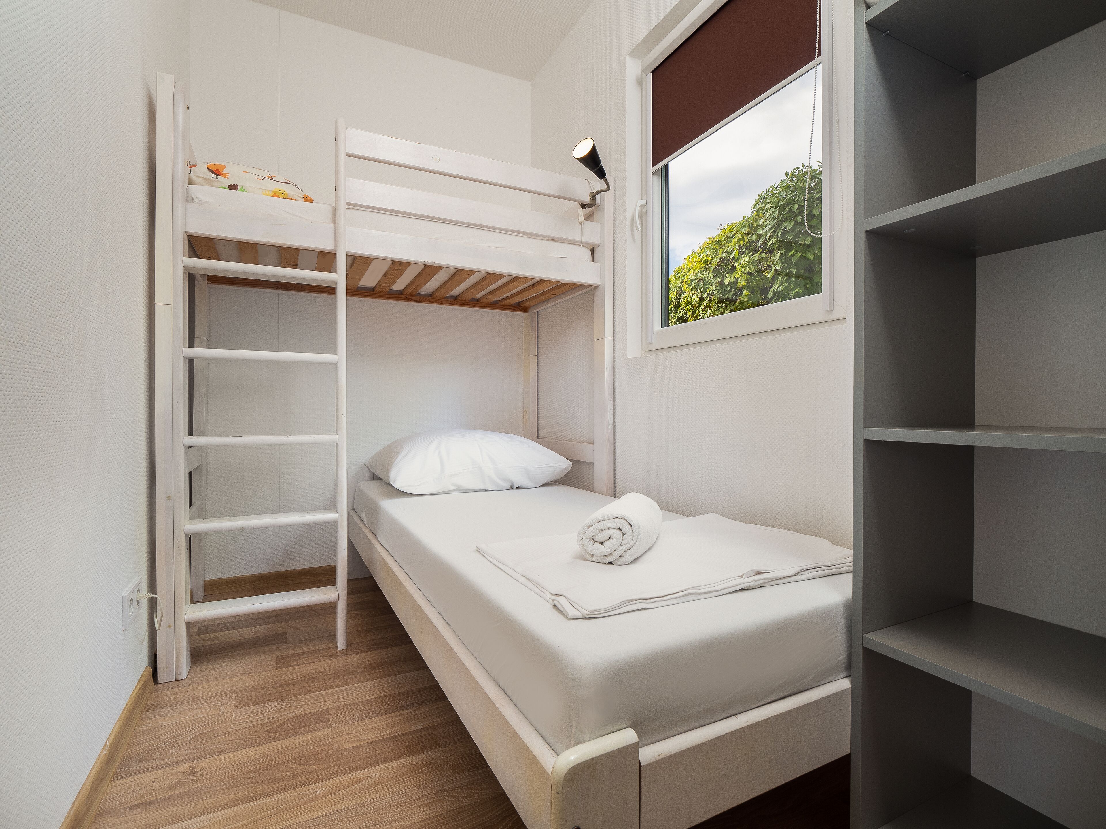 Habitación con literas, una ventana, una escalera y una estantería.