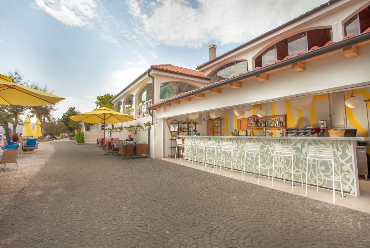 An outdoor café with a bar area, outdoor seating, and umbrellas.