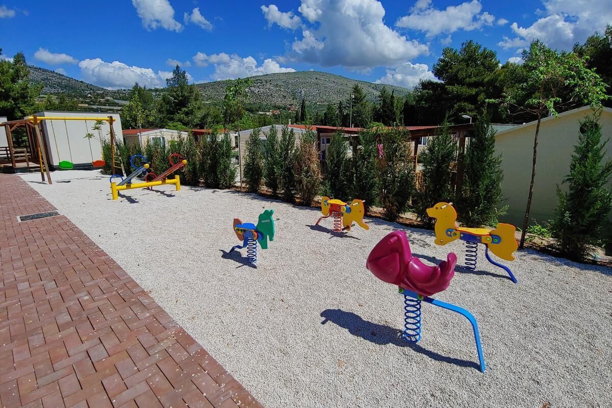 Ein Spielplatz mit verschiedenen Spielgeräten, darunter Schaukeln, eine Rutsche und Klettergerüste.