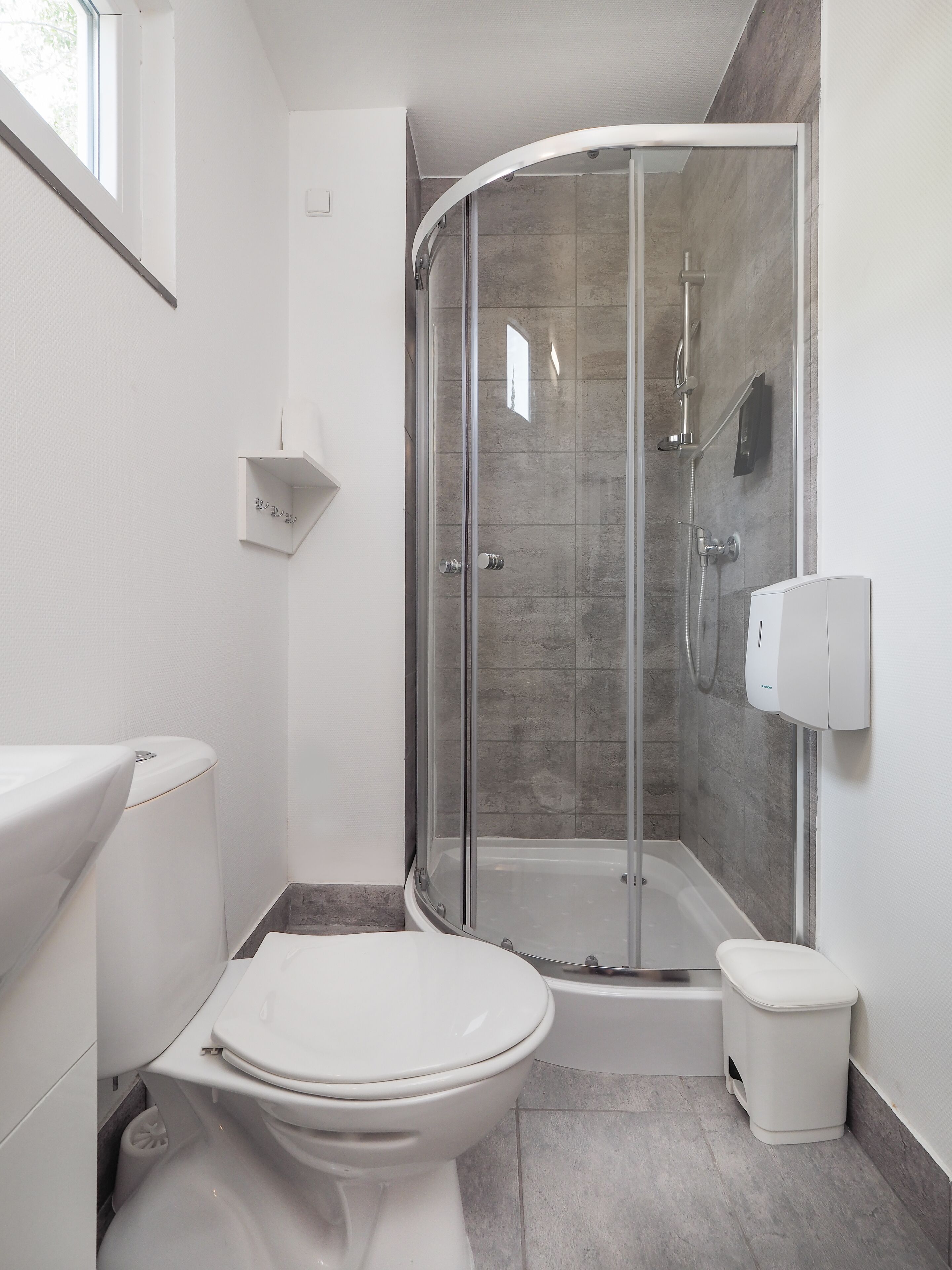 A modern bathroom with a glass-enclosed shower, a white toilet, and a white sink.