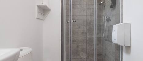 A modern bathroom with a glass-enclosed shower, a white toilet, and a white sink.