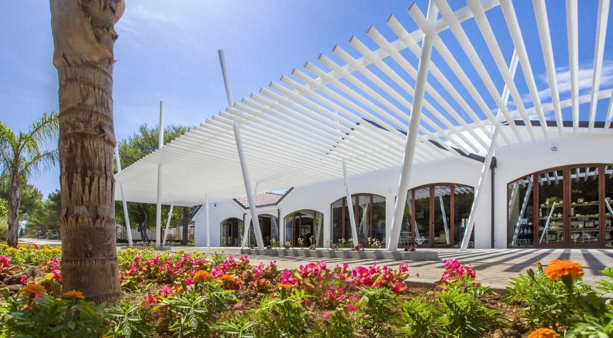 A modern building with a white exterior, large windows, and a covered outdoor area with a white roof structure.
