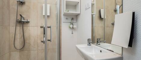 A modern bathroom with a glass shower enclosure, a white sink, and a large mirror.