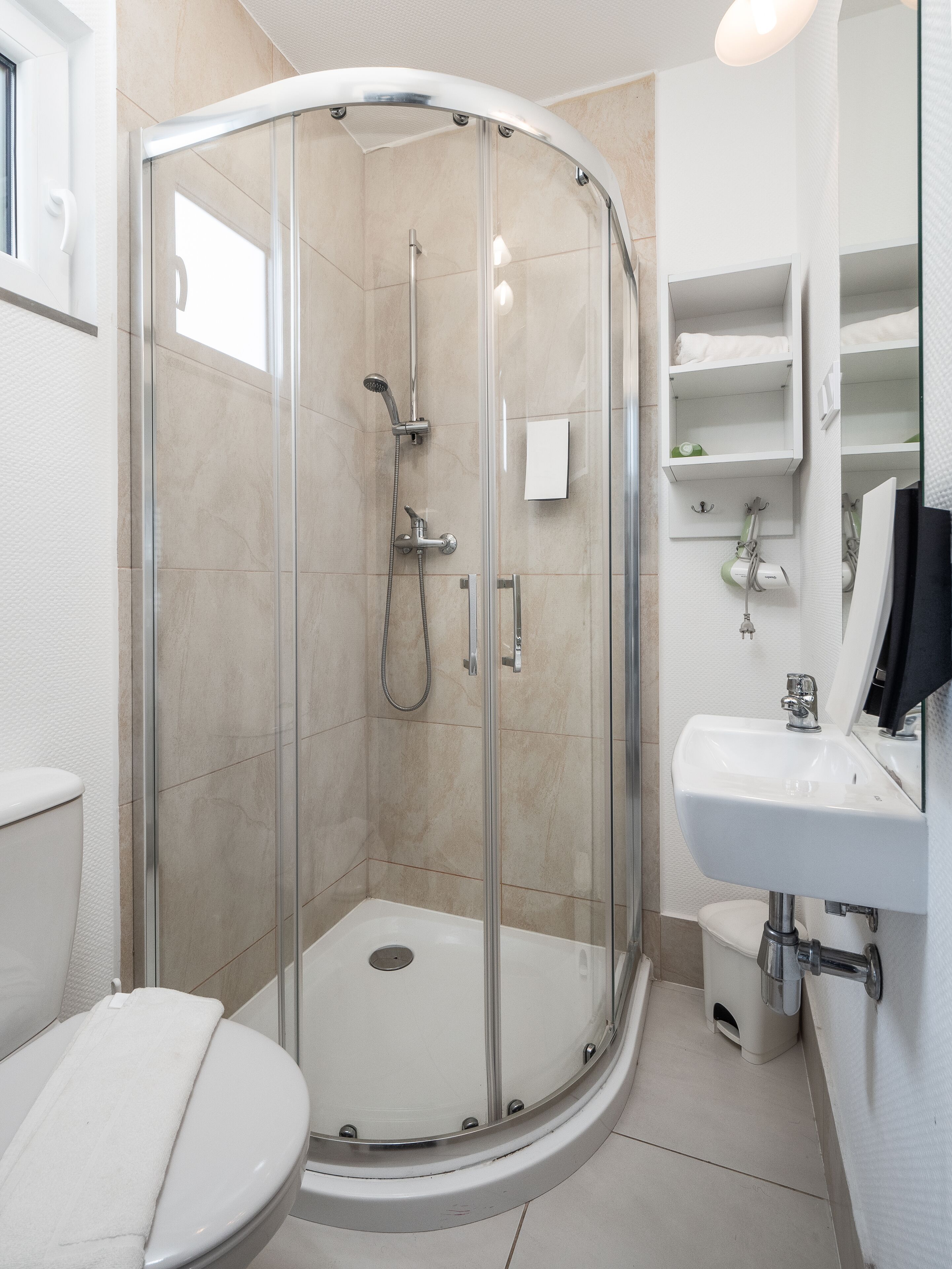 A modern bathroom with a glass-enclosed shower, a white sink, and a toilet.