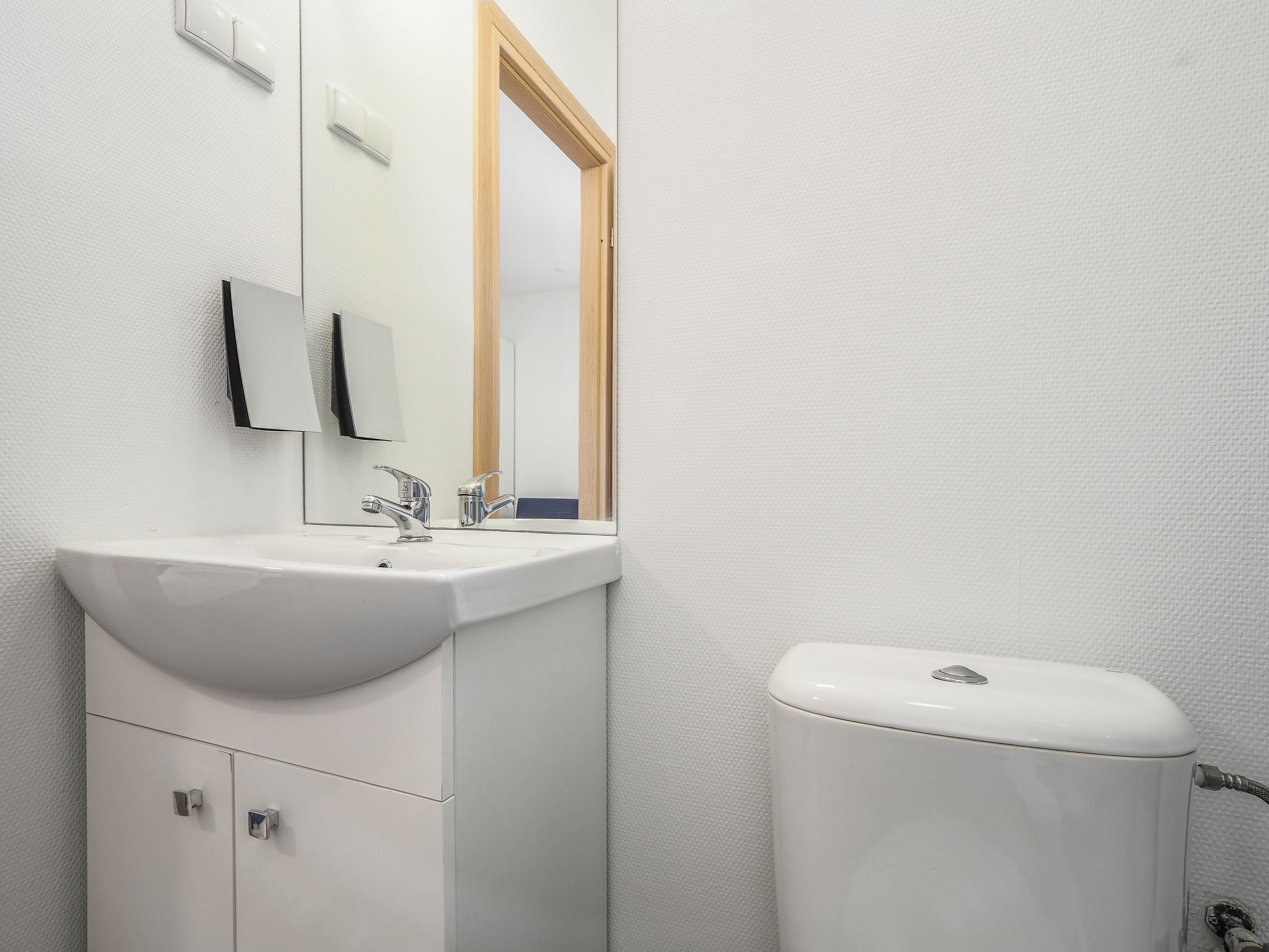 Et badeværelse med vask, spejl og toilet.