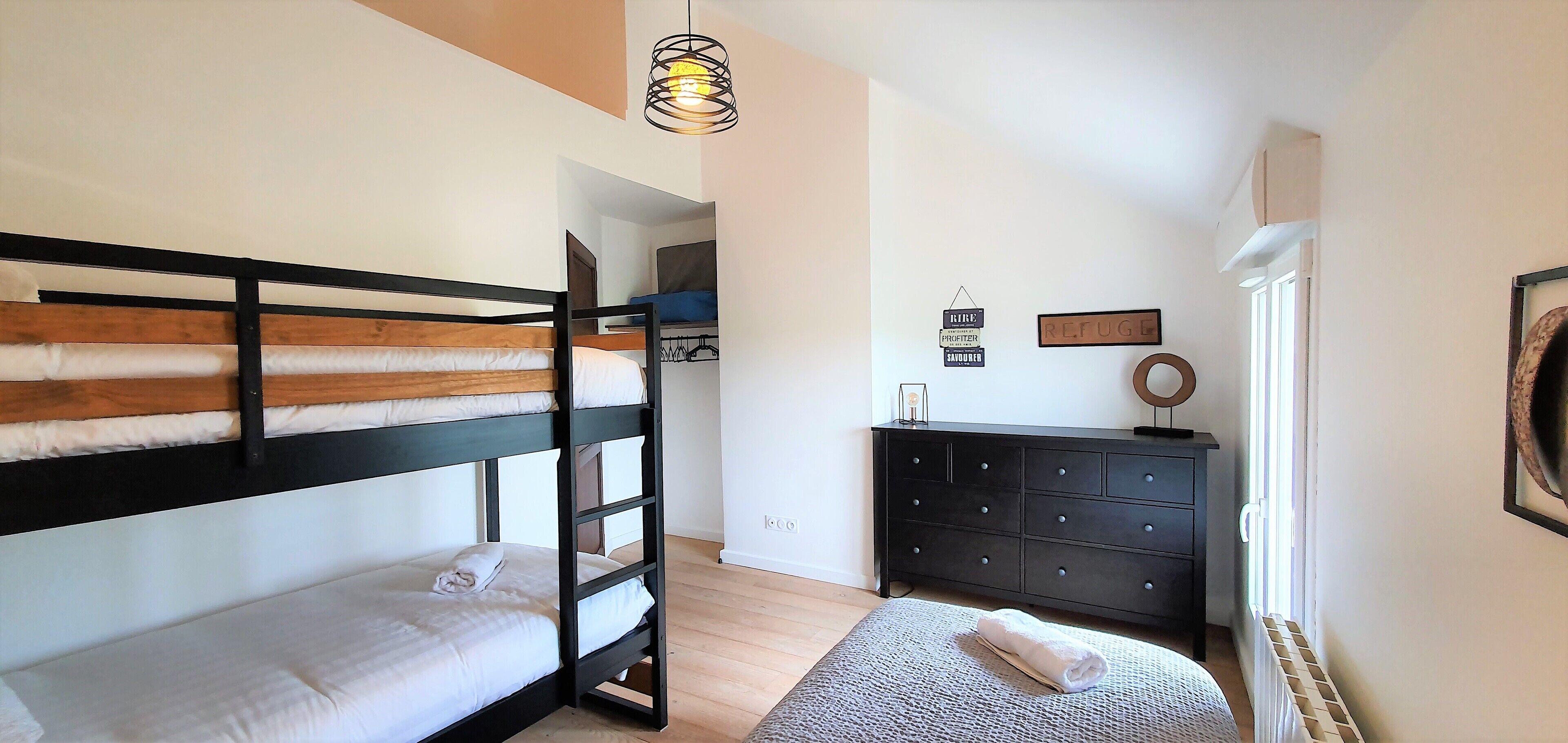 Une chambre de type dortoir, avec des lits superposés, une commode et un radiateur.