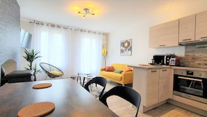 Een moderne keuken met een ingebouwde oven en een eethoek met een houten tafel en stoelen.