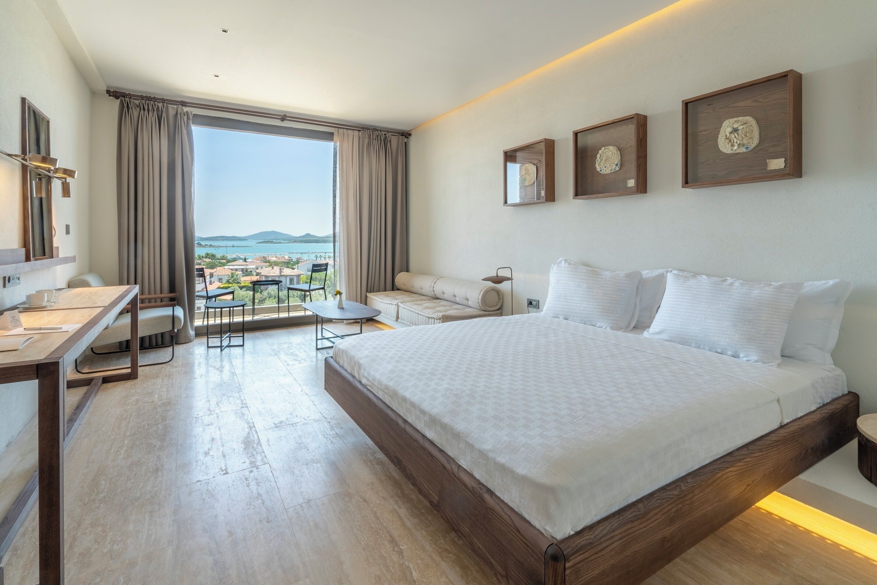 Habitación de hotel moderna con una cama grande, un escritorio y un balcón con vista al mar.