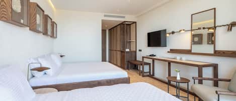 A modern hotel room with two beds, a desk, a chair, a TV, and a mirror.
