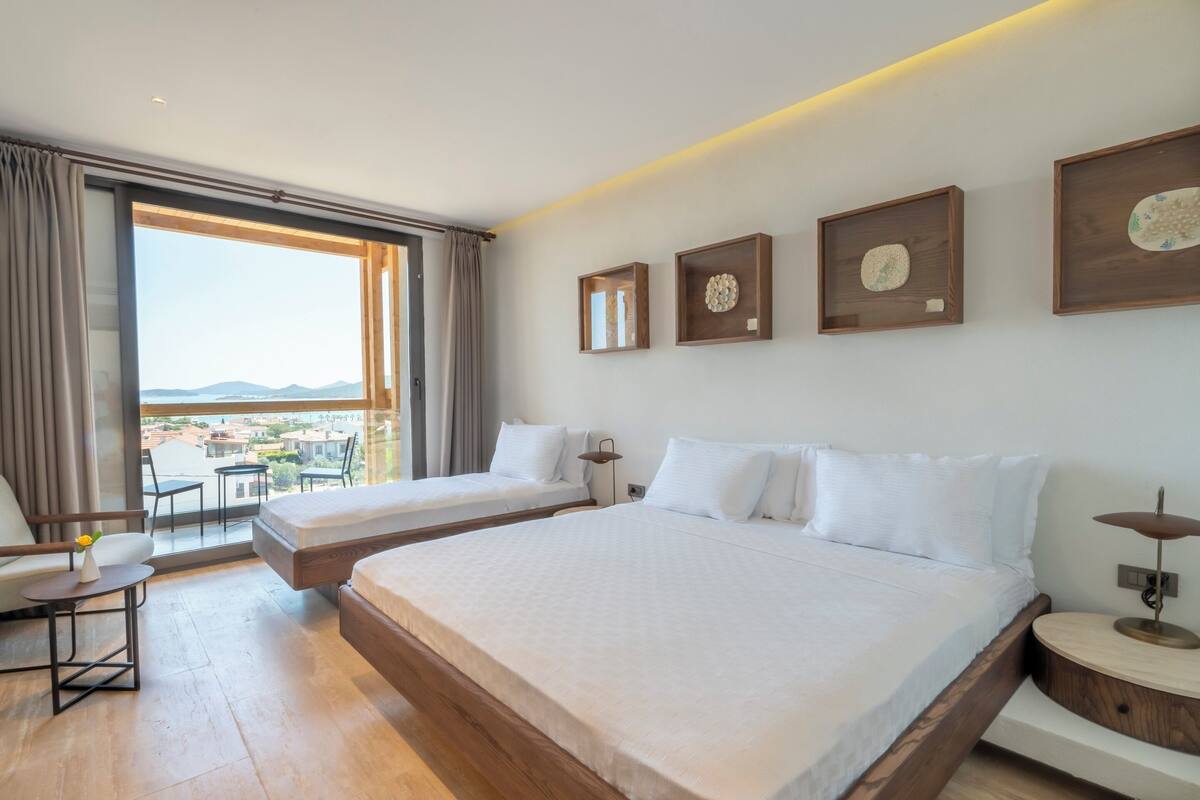 A hotel room with two beds, a large window with a view, and wooden decor.