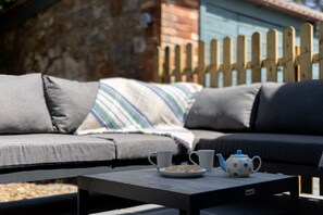 Relax in a serene outdoor space with a comfortable sofa and a small table for a quiet morning moment.