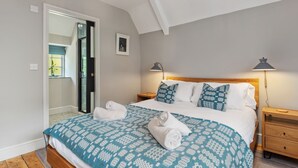 Een slaapkamer met een bed, twee nachtkastjes, een lamp en een deur naar een badkamer.