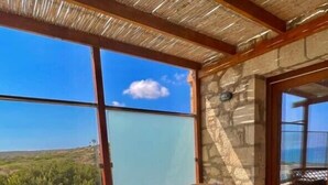 Een balkon met rieten meubels en een glazen tafel, met uitzicht op een prachtig landschap.
