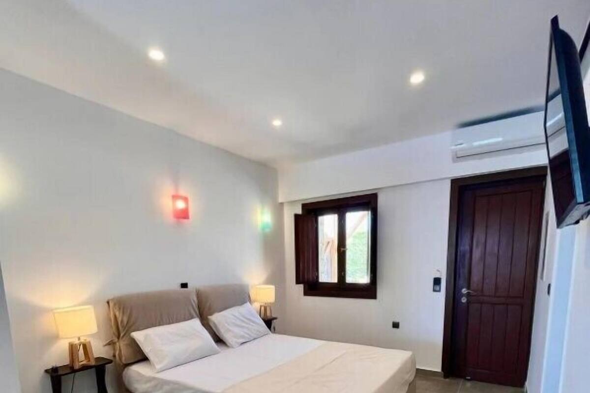A bedroom with a bed, bedside tables, a chair, a window, and a door.