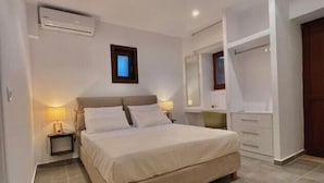 Een slaapkamer met een bed, nachtkastjes, een spiegel en een airconditioning.