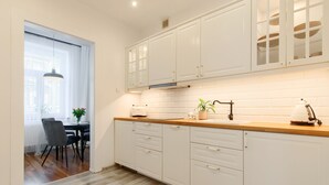 Une cuisine moderne avec des meubles blancs, un plan de travail en bois et une fenêtre ornée de rideaux légers.