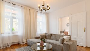 Un salon moderne avec un canapé, une table basse ronde et un lustre.