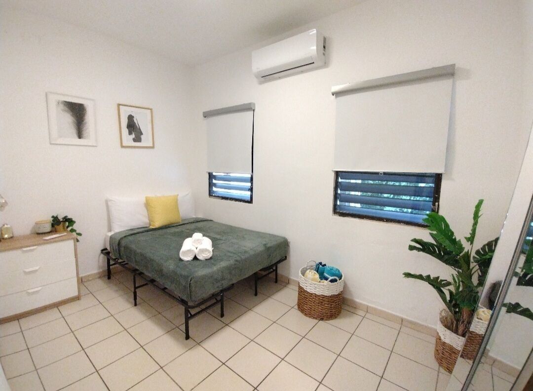 A bedroom with a bed, a dresser, a mirror, and a potted plant.