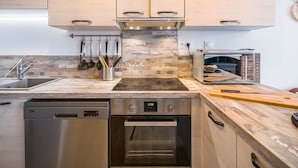Una cucina moderna con mobili in legno, forno integrato, lavastoviglie e microonde.