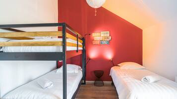 Ein Schlafsaalzimmer mit Etagenbetten, einer roten Wand, einer Globenlampe und einer Wand mit motivierenden Sprüchen.