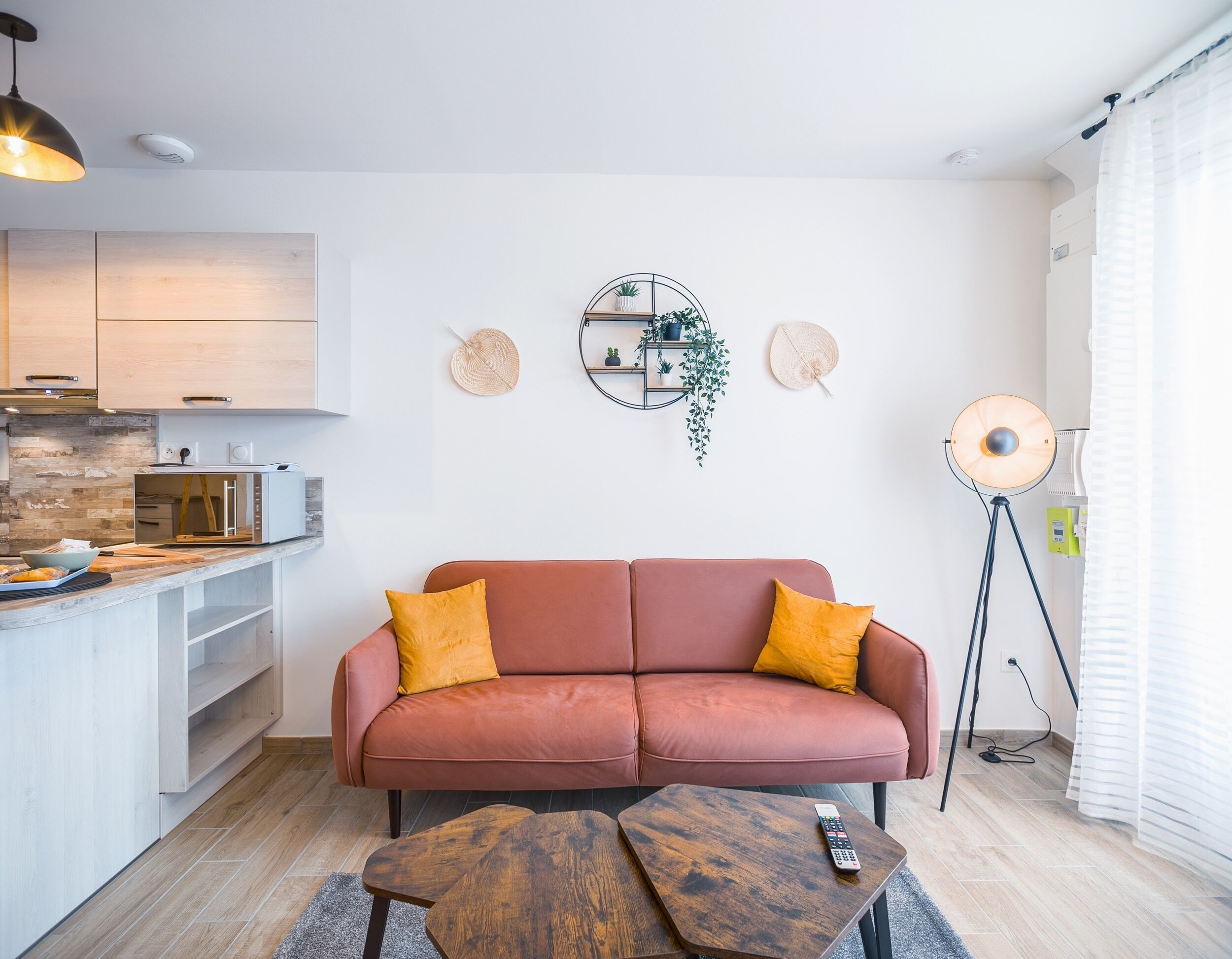A modern living room with a sofa, a coffee table, a kitchen area, and a floor lamp.